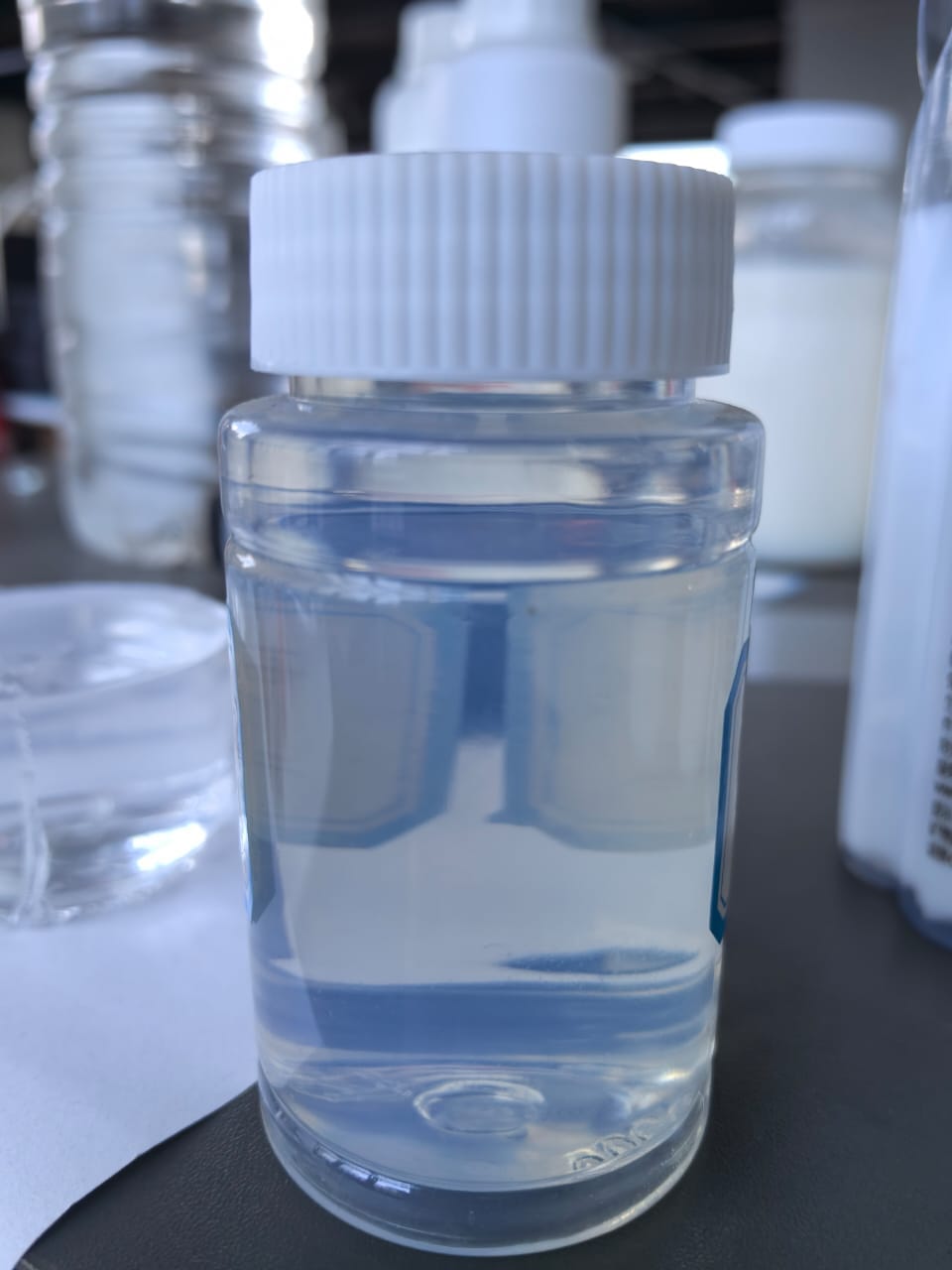 Small clear bottle of colorless liquid with a white ribbed cap