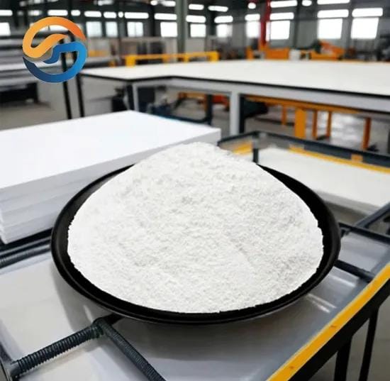 Mound of white resin powder on a black tray in a factory workspace