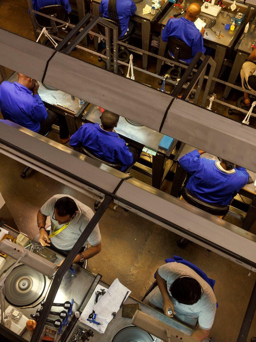 Overhead view of diamond cutting and polishing workstations with technicians in blue uniforms