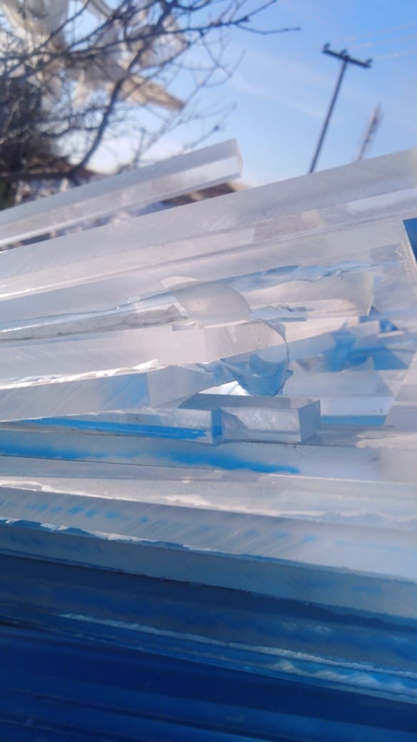 Thick clear acrylic sheet scrap stacked outdoors under open sky