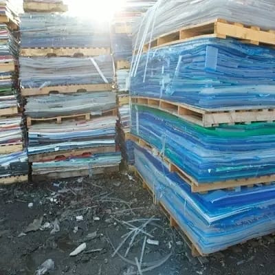 Blue acrylic sheet stacks wrapped on wooden pallets outdoors