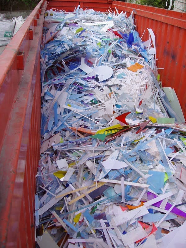 Mixed white and colored plastic scrap filling an industrial skip